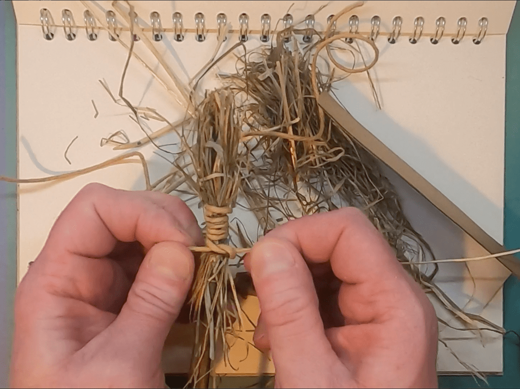 tying a knot to hold hay brush together image