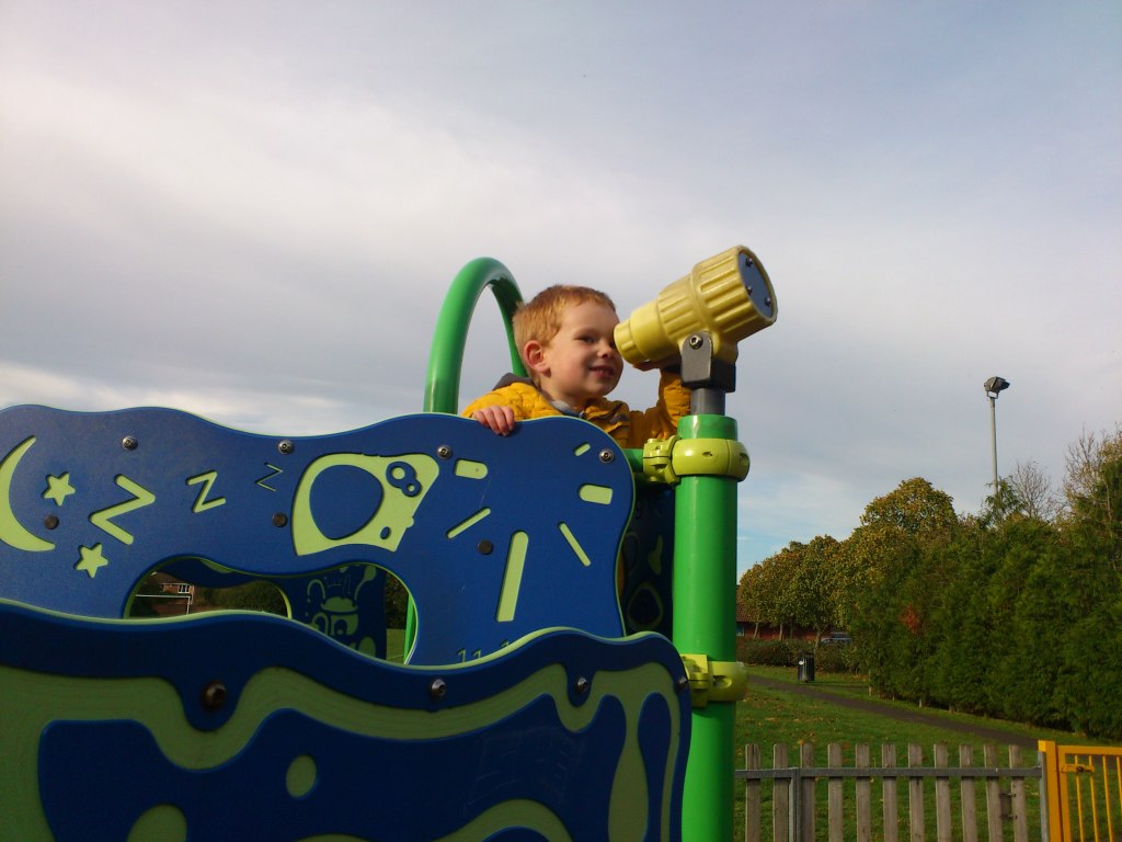 boy looking through a telescope in a playground